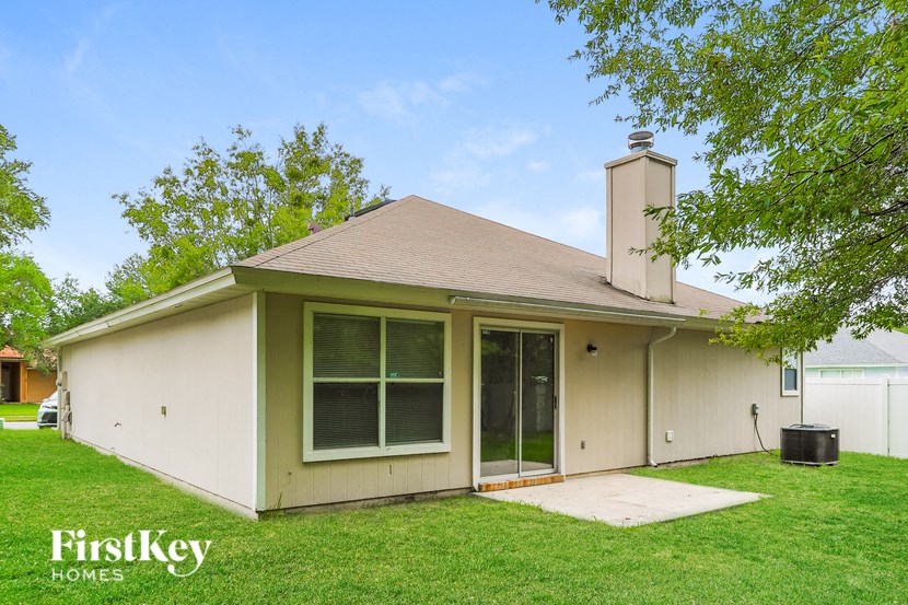 the front of a white house with a lawn and trees