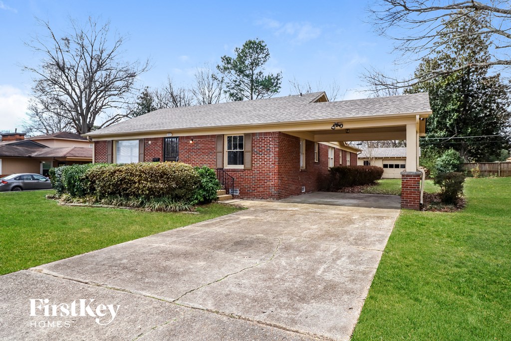 a brick house with a driveway and a covered porch