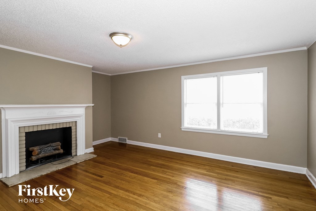 the living room of a house with a fireplace and wooden floors