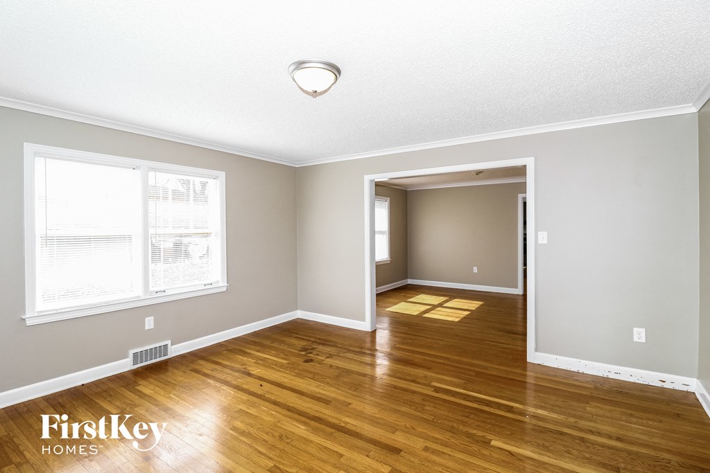 the living room and dining room of a house with wood flooring and a window
