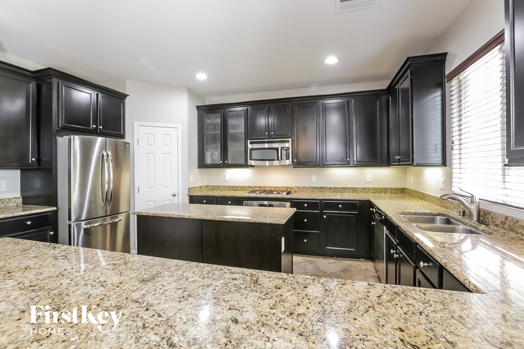A kitchen with black cabinets and granite countertops.