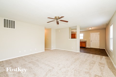 A spacious room with a ceiling fan and carpeted floor.