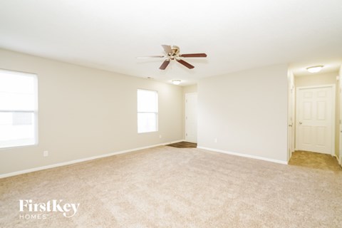 A spacious room with a ceiling fan and two windows.
