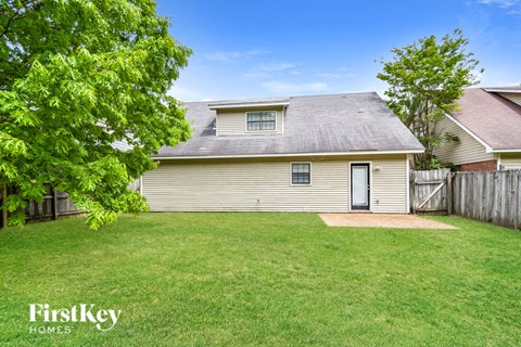 A house with a green lawn and trees in the background.
