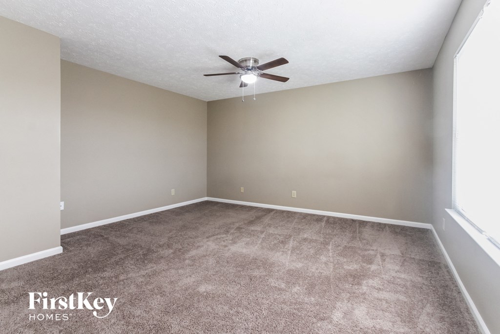 an empty living room with carpet and a ceiling fan
