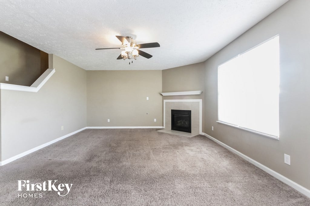 an empty living room with a ceiling fan and a fireplace