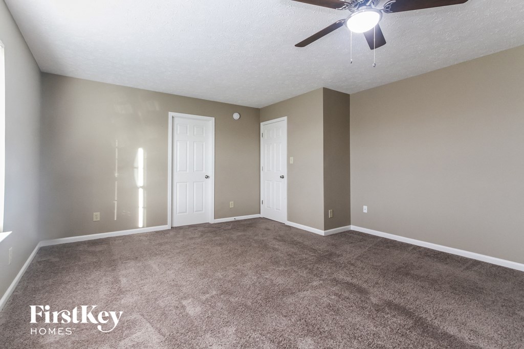 an empty living room with carpet and a ceiling fan