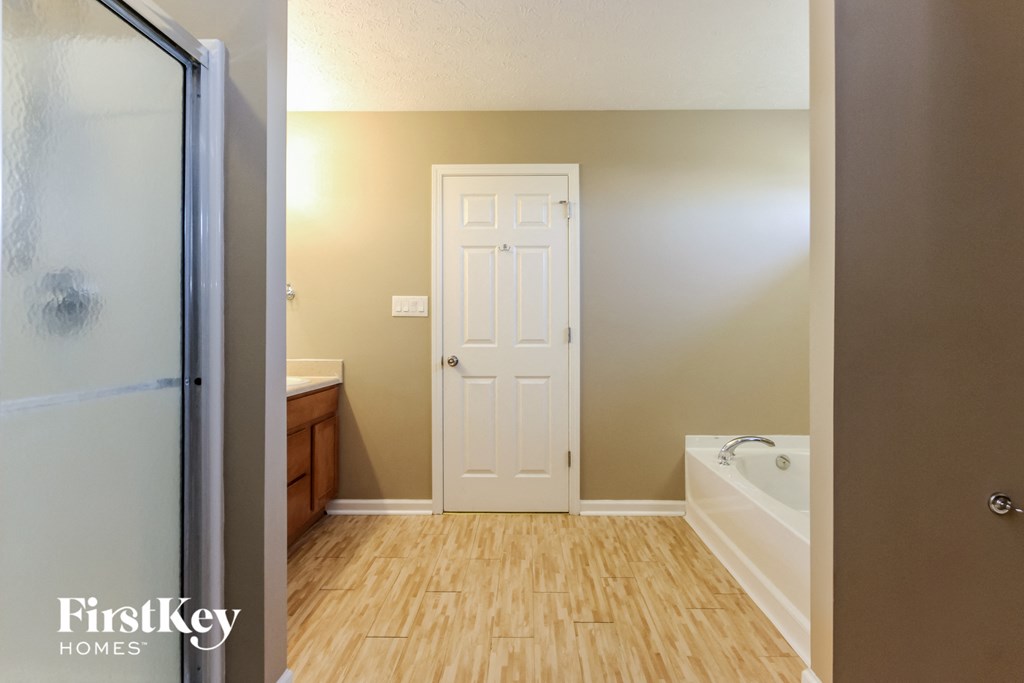a bathroom with a shower door and a sink and a tub