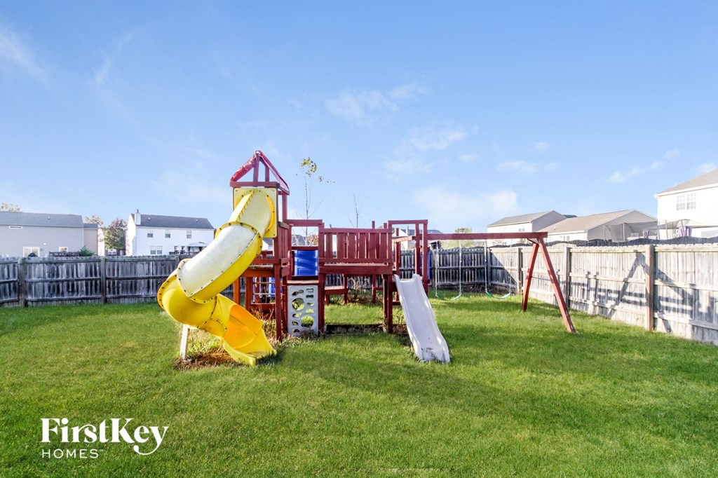 a playground with a yellow slide and a red playset