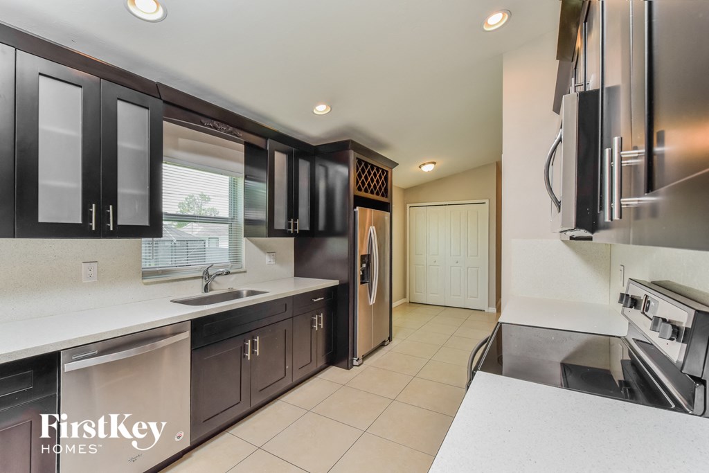 a kitchen with black cabinets and white countertops and a stainless steel refrigerator