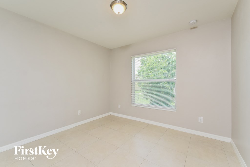 an empty room with a large window and tiled floors