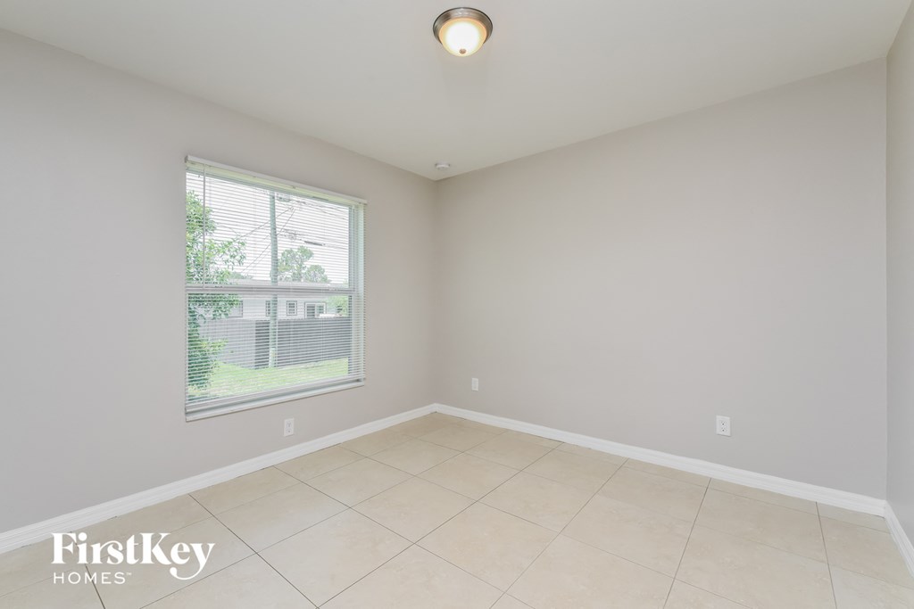 an empty room with a large window and a tiled floor