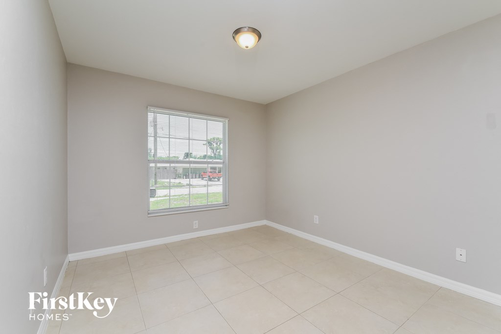 an empty living room with a large window and tiled floors