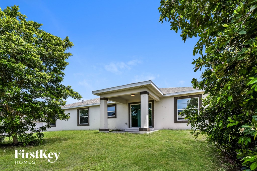 a white house with a lawn and trees