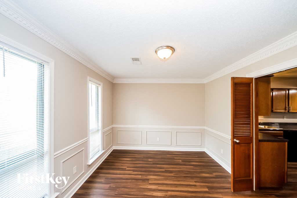 an empty dining room with wood floors and white walls