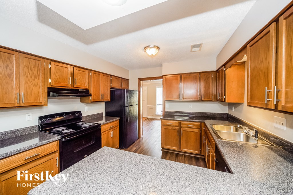a kitchen with wood cabinets and black appliances and granite counter tops