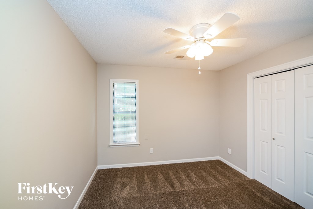a spacious bedroom with carpet and a ceiling fan