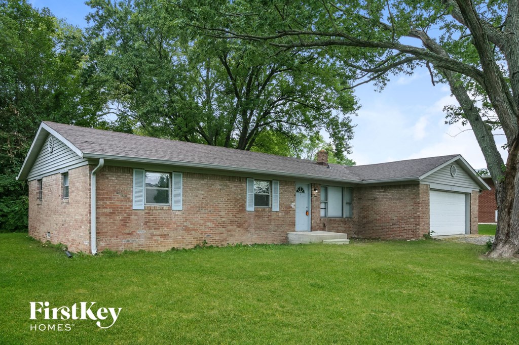 front view of a brick house with green grass and trees