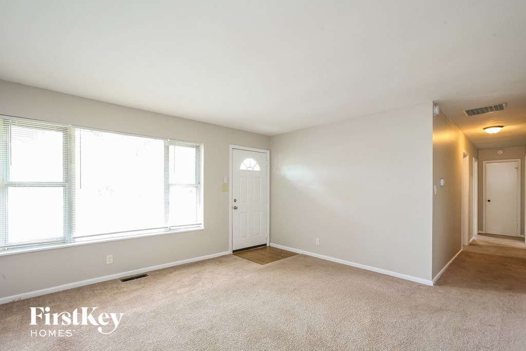 a bedroom with a door and two windows and a carpeted floor