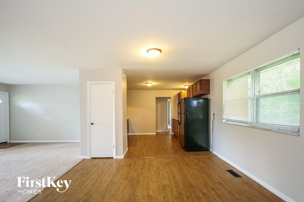 the living room of an apartment with a refrigerator and a window