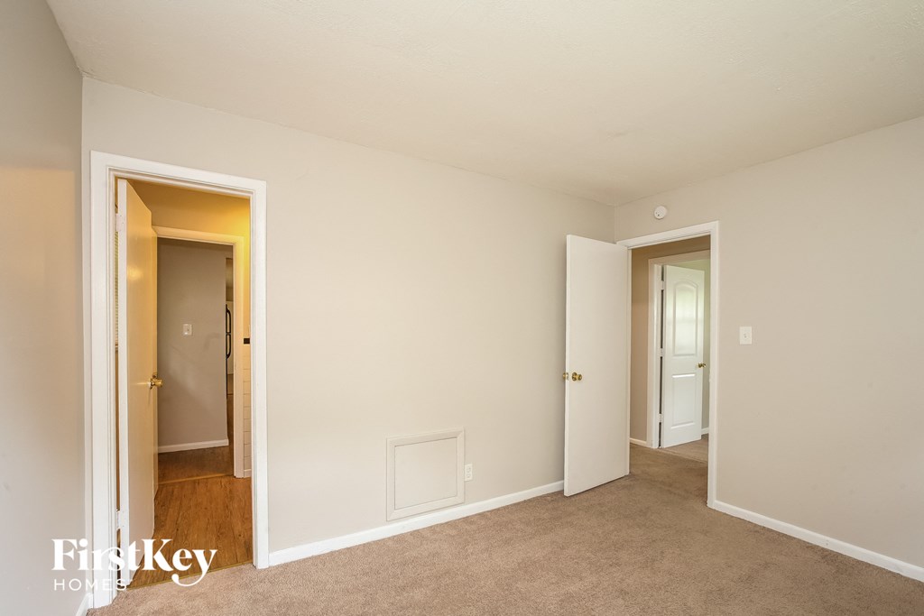 a bedroom with a carpeted floor and a door to a hallway