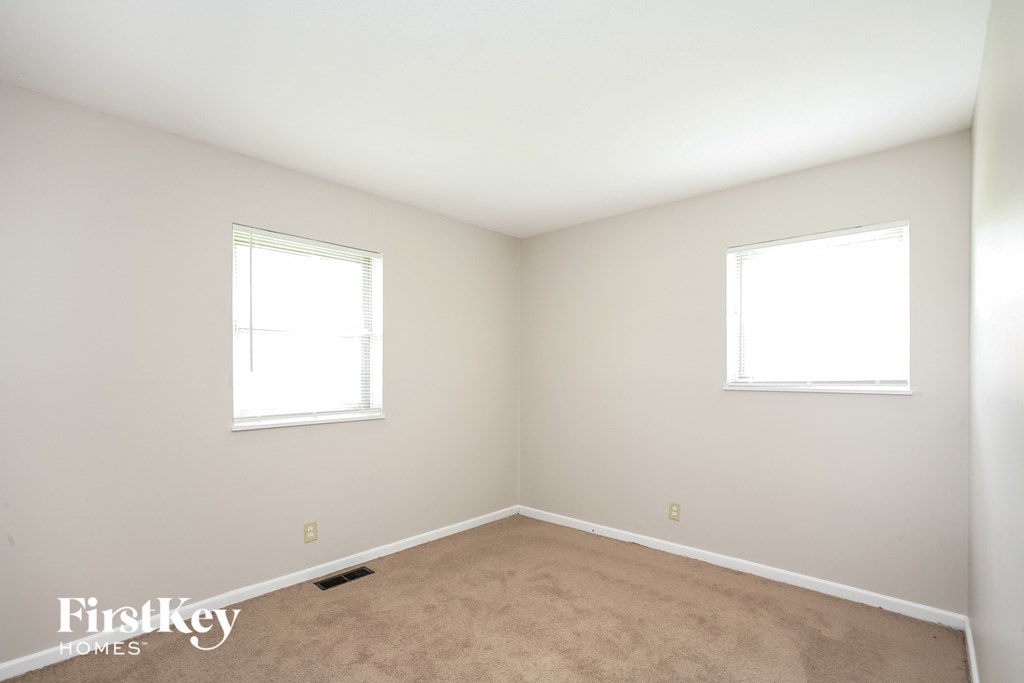 a bedroom with two windows and a carpet