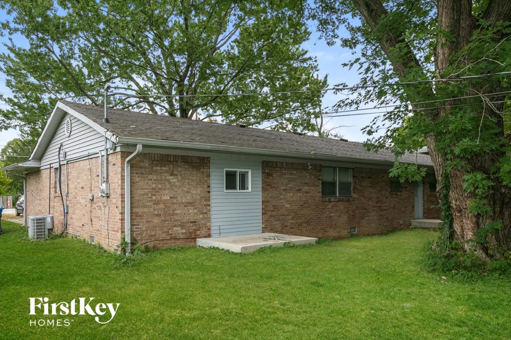 the front of a brick house with a yard and a tree
