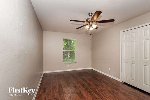 the spacious living room with wood flooring and a ceiling fan
