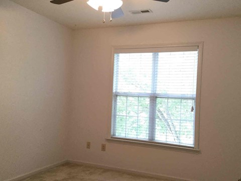 a living room with a window and a ceiling fan
