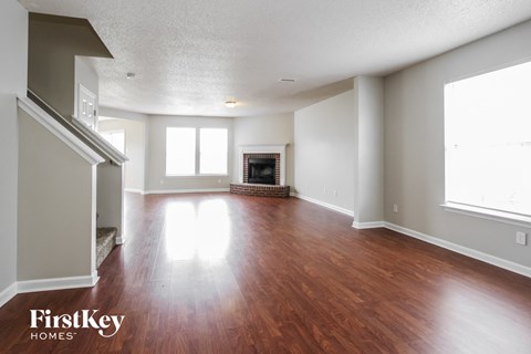 an empty living room with wood floors and a fireplace