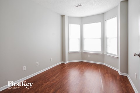 a room with a hard wood floor and three windows