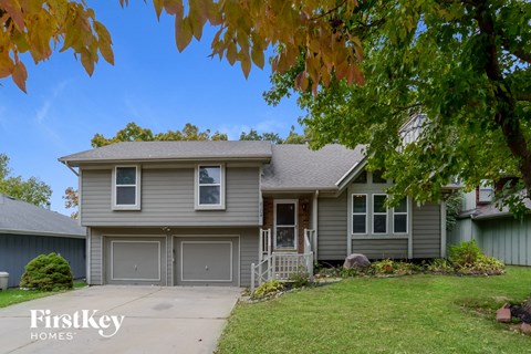 a gray house with a lawn and a tree