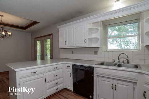 a white kitchen with white cabinets and a black dishwasher