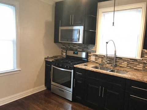 A kitchen with black cabinets and a stainless steel oven.