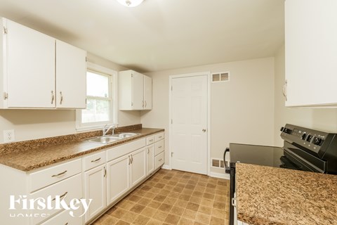 A kitchen with white cabinets and a granite counter top.