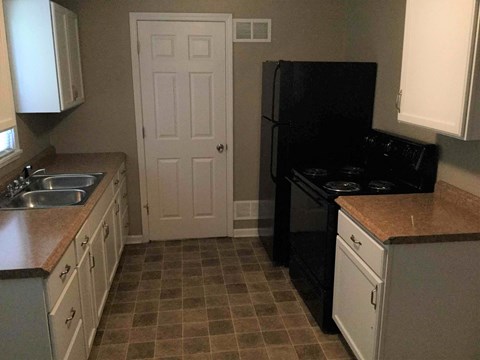 A kitchen with a black fridge and white cabinets.