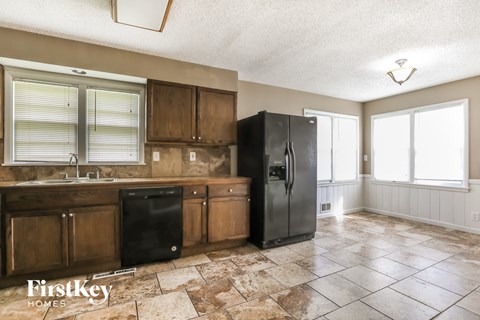 A kitchen with a black fridge and wooden cabinets.