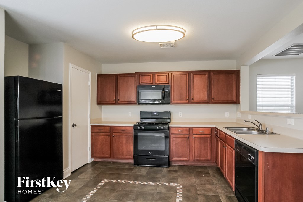 an empty kitchen with wooden cabinets and black appliances
