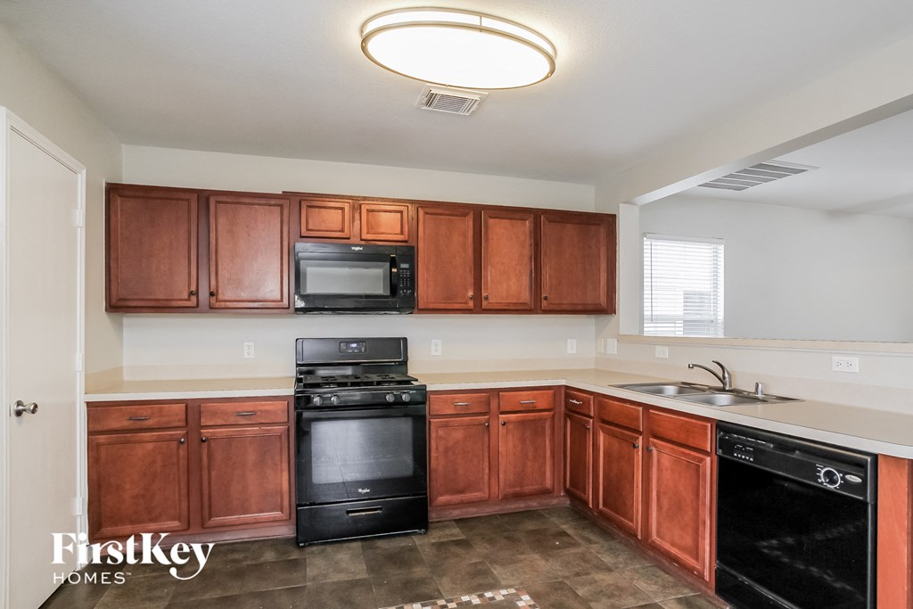an empty kitchen with wooden cabinets and black appliances