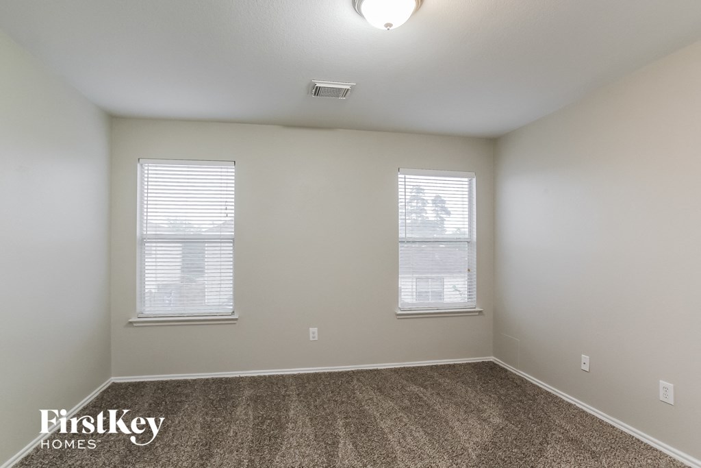 a bedroom with two windows and a carpeted floor
