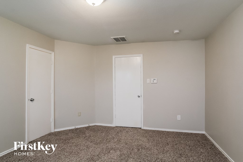a bedroom with white walls and carpet and two doors