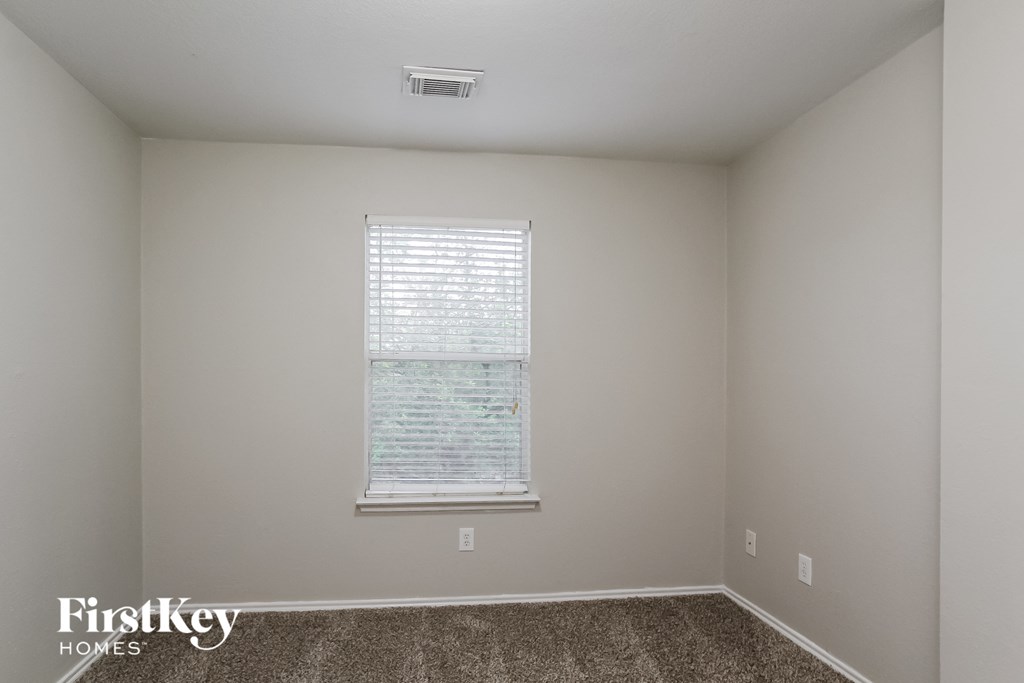 a bedroom with a window and a carpeted floor