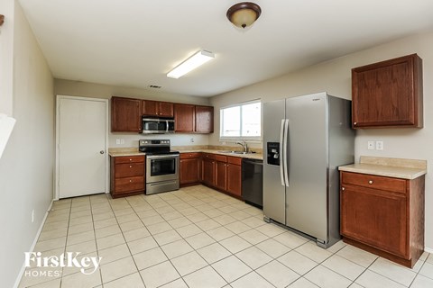 A kitchen with a refrigerator, oven, microwave, and sink.