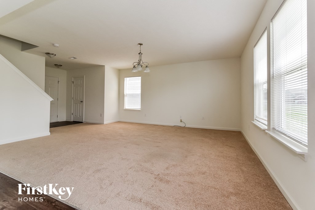 A spacious room with a carpeted floor and a chandelier hanging from the ceiling.
