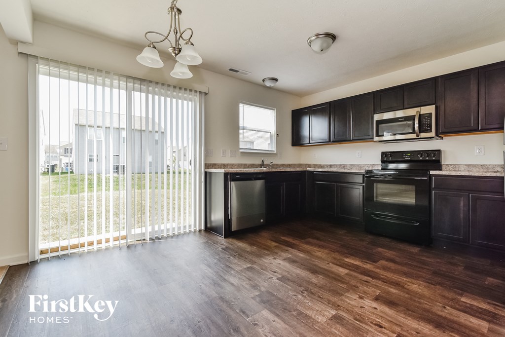 A kitchen with dark wood cabinets and a black stove top oven.