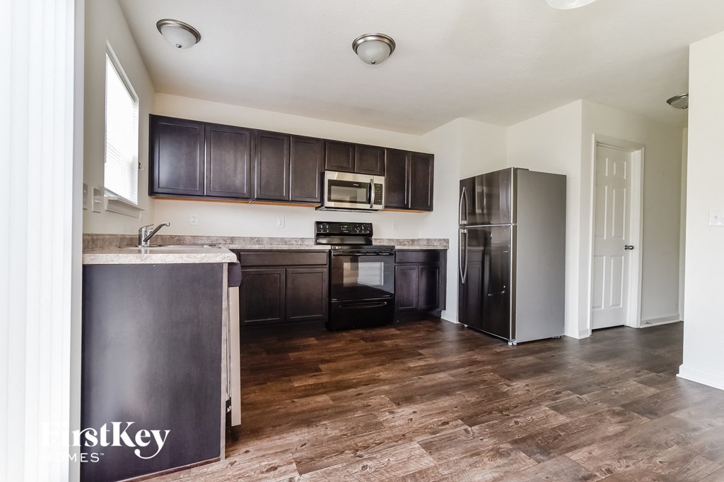 A kitchen with dark brown cabinets and a wooden floor.