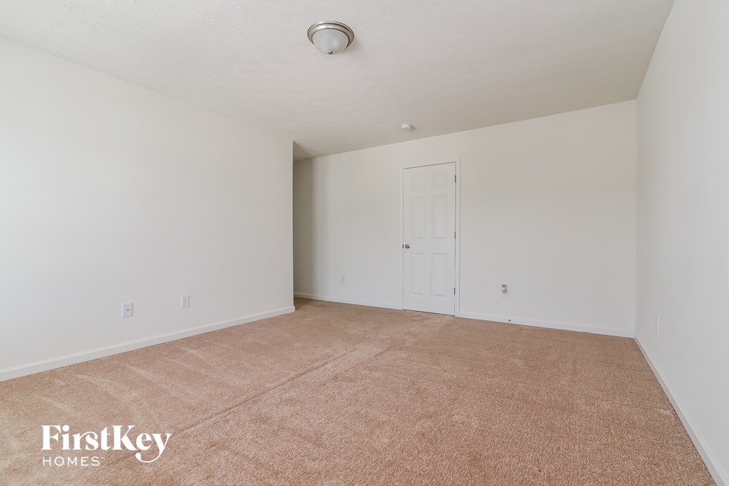 A room with a carpeted floor and a door on the right side.