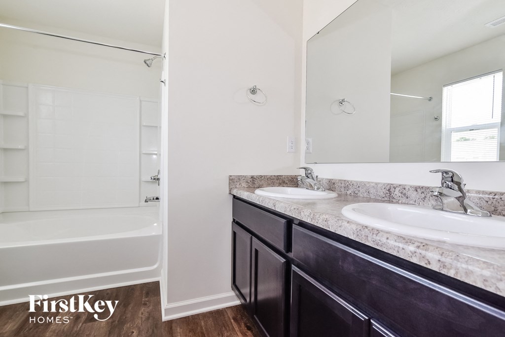 A bathroom with a tub, sink, and mirror.