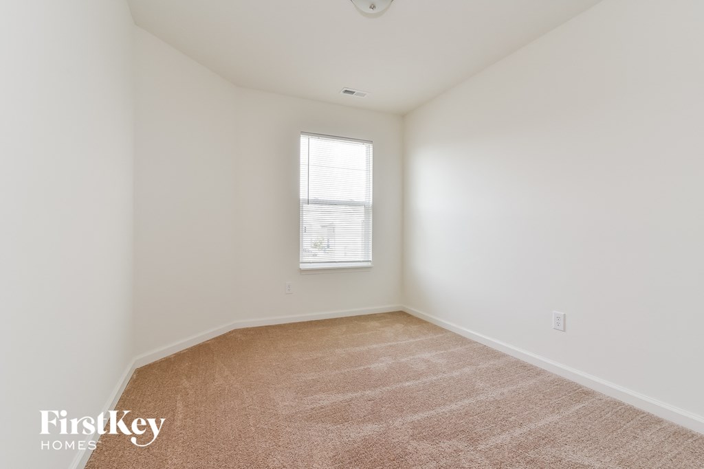 A room with a carpeted floor and a window with blinds.