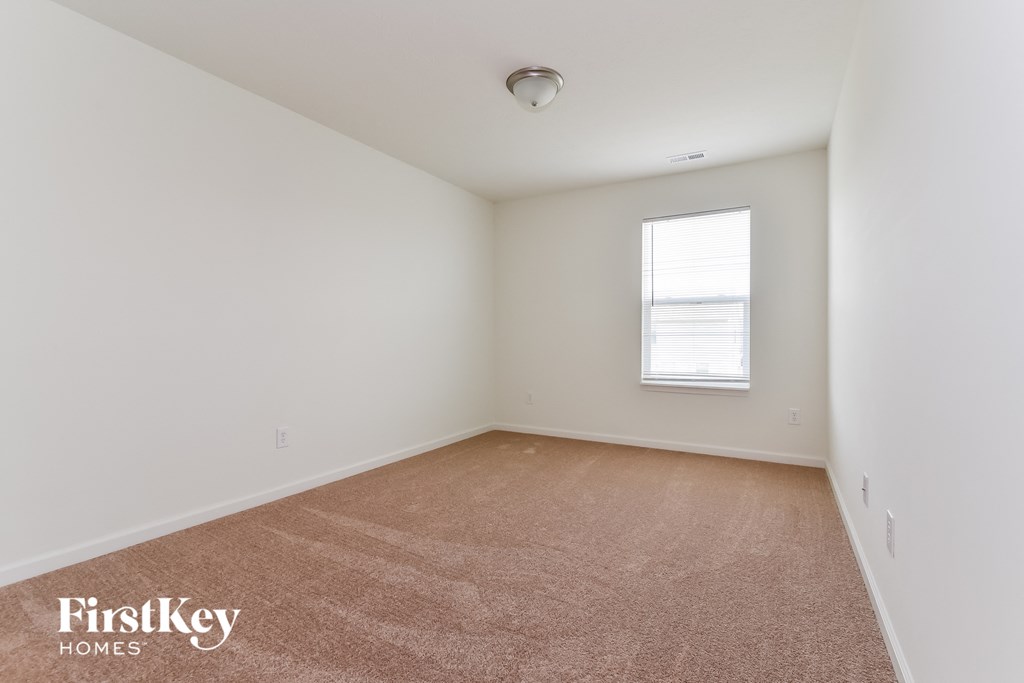 A room with a carpeted floor and a window letting in natural light.